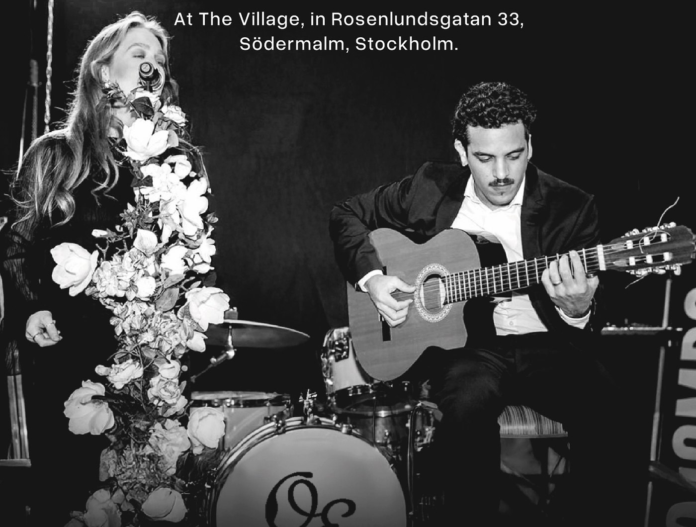 Vilma Olsson singing beside Danel Estrada playing acoustic guitar, in a black and white performance photograph.
