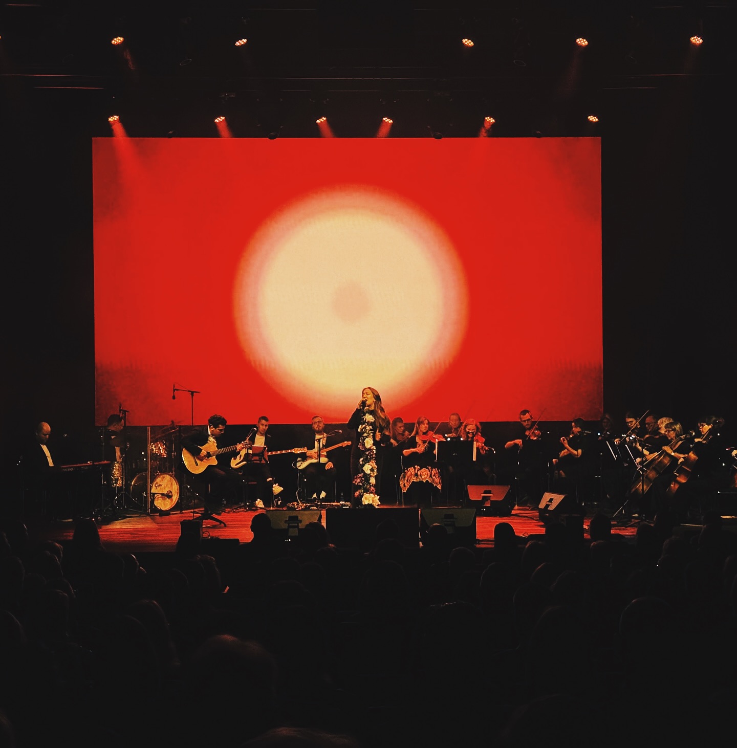 A wide view of the special orchestral performance and its red stage backdrop.